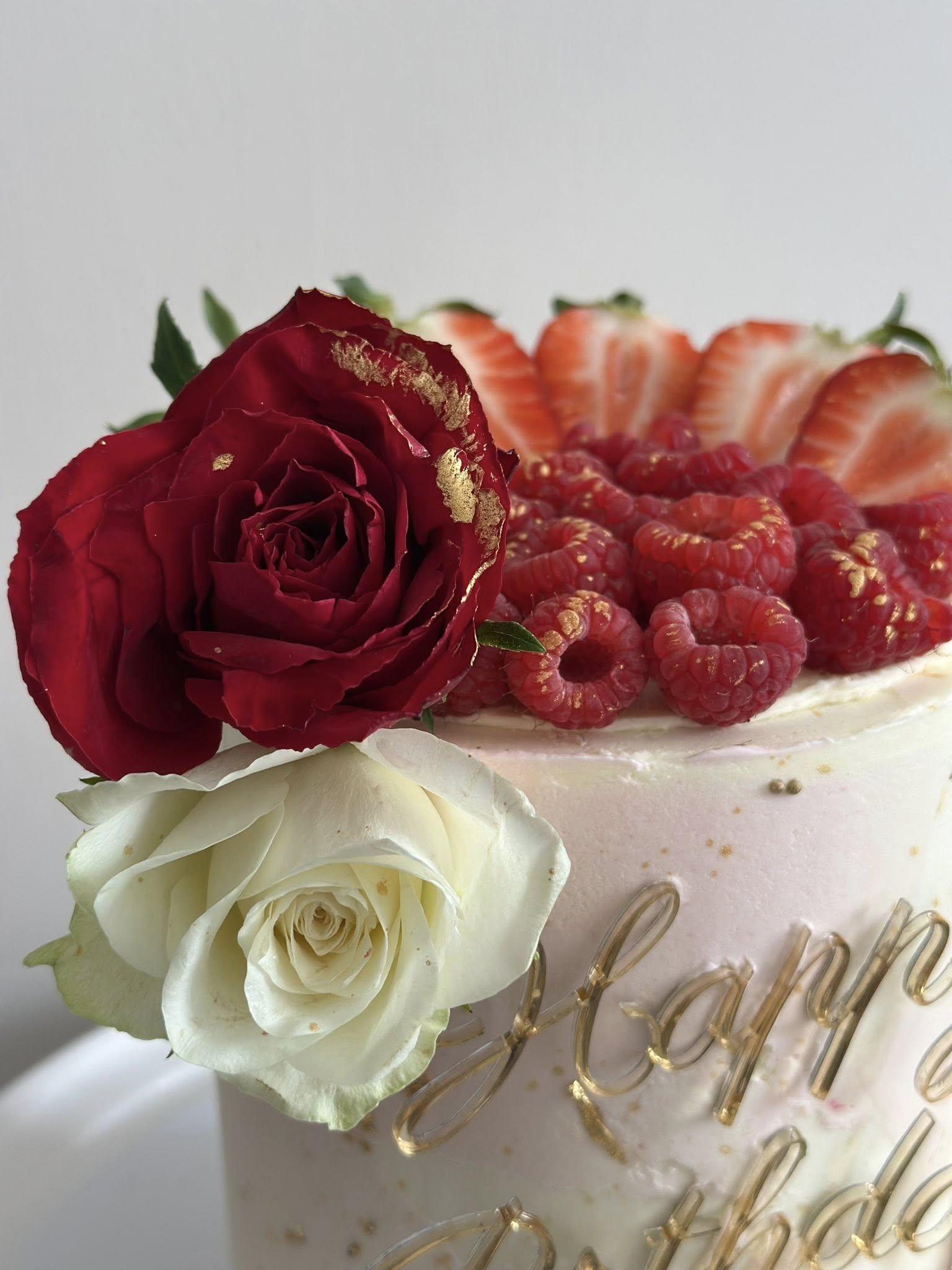Elegant tiered cake with red roses and raspberries