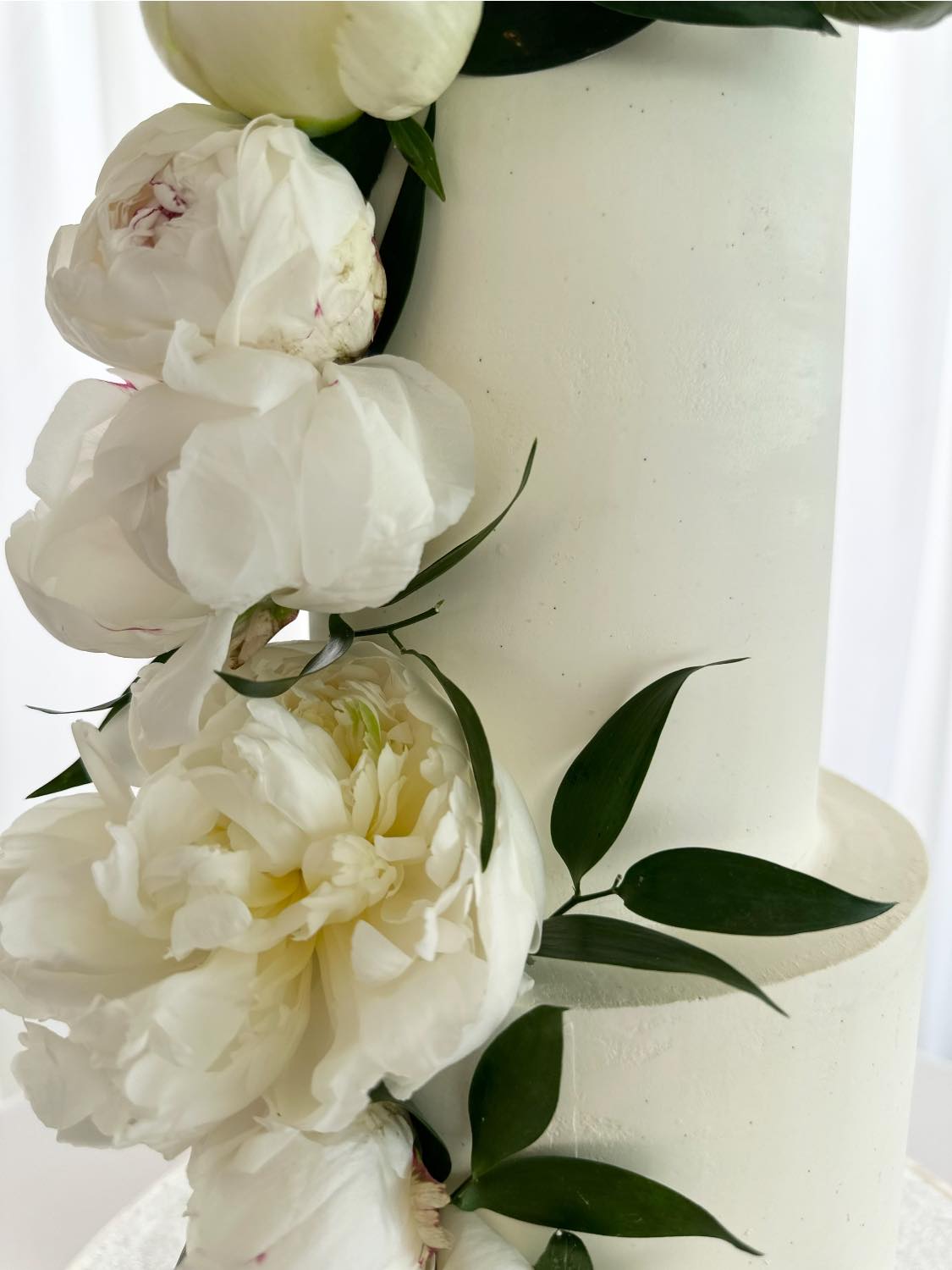 White frosted cake decorated with cream peonies