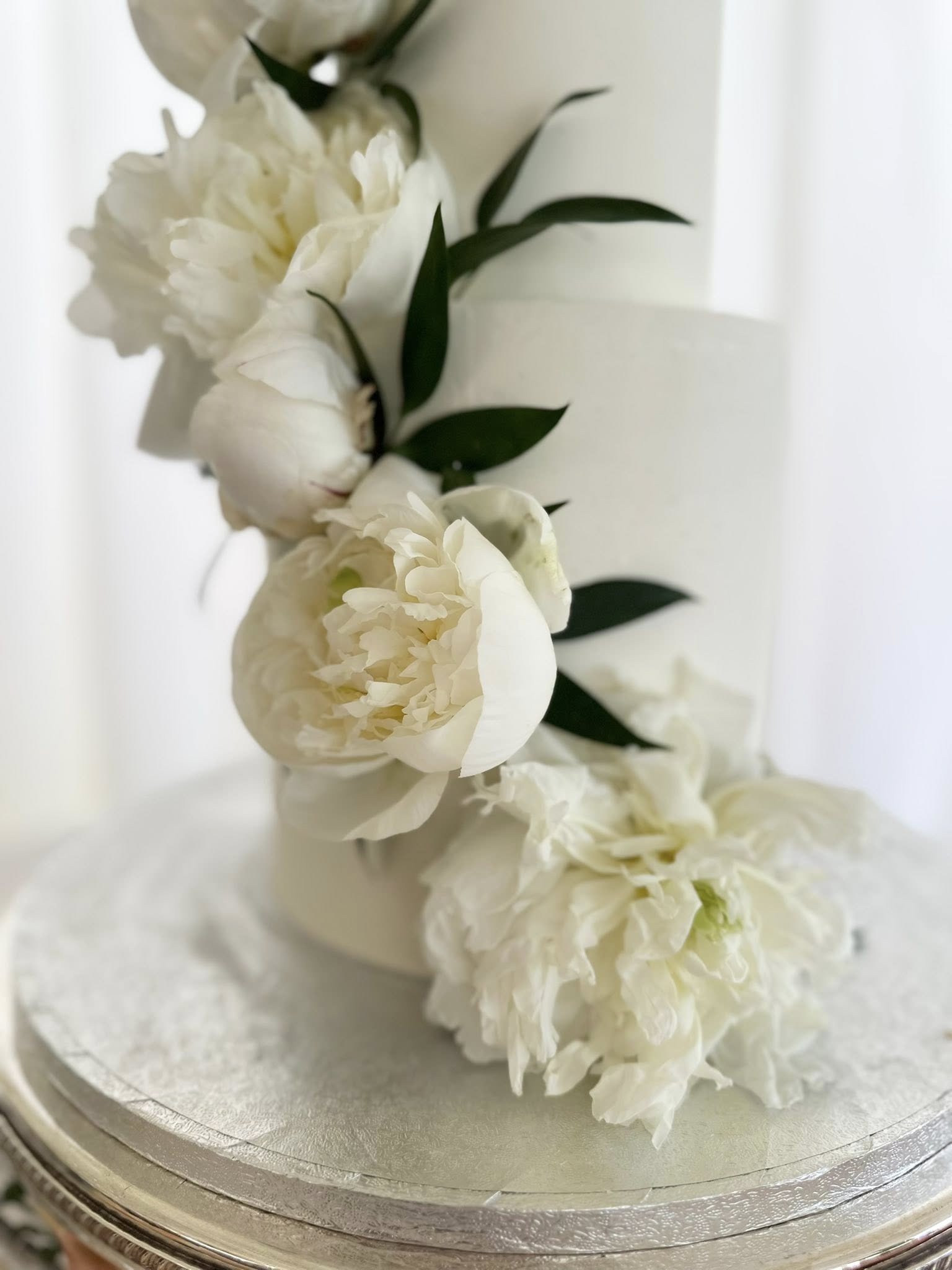 White tiered wedding cake with fresh peonies