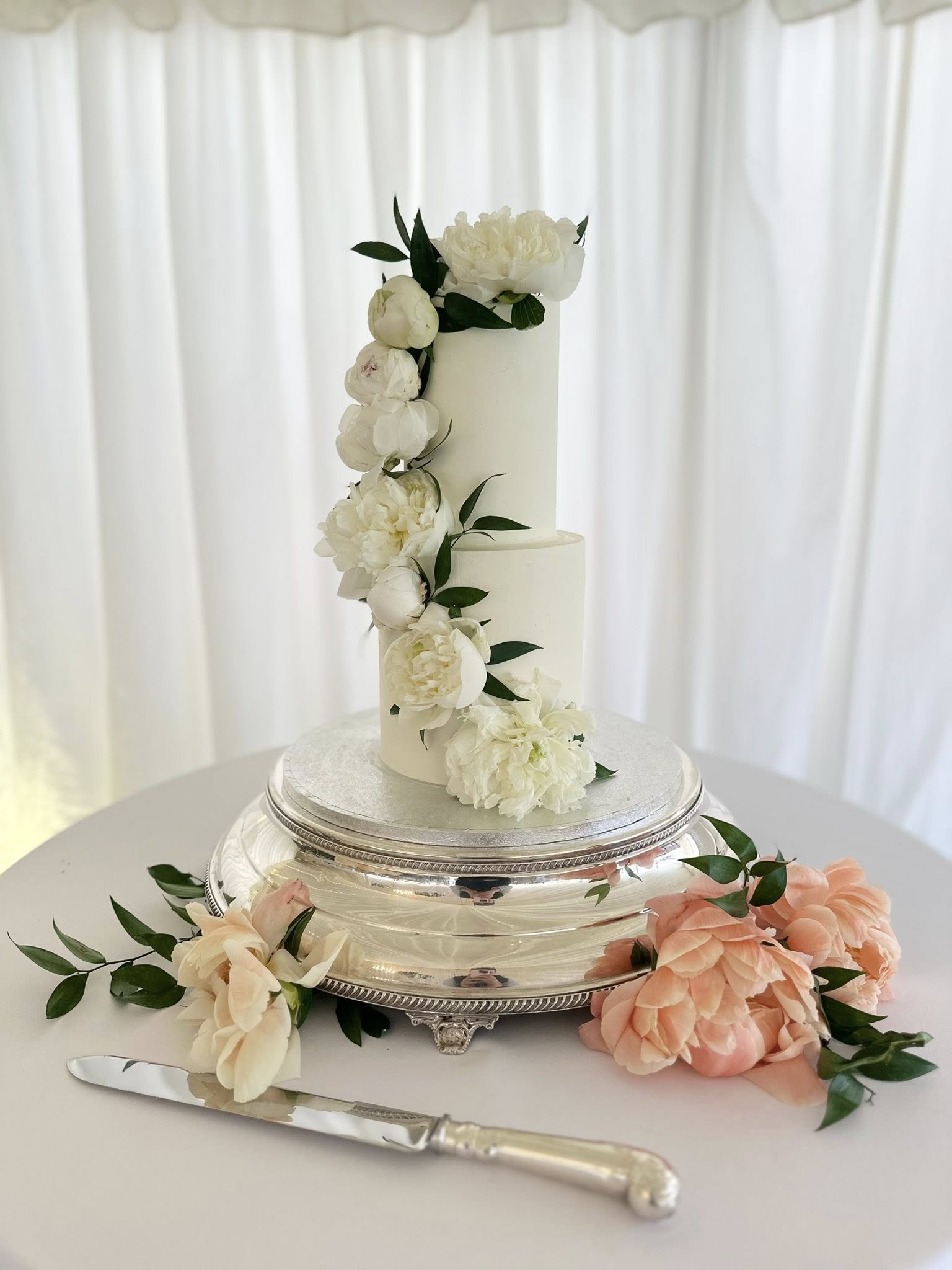 Elegant two-tier white wedding cake with peonies
