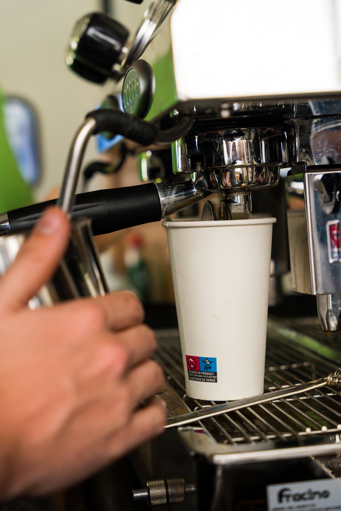 Espresso machine dispensing coffee into paper cup