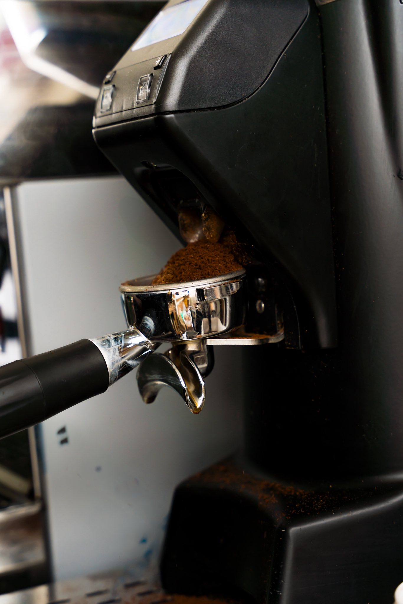 Espresso machine dispensing freshly ground coffee grounds