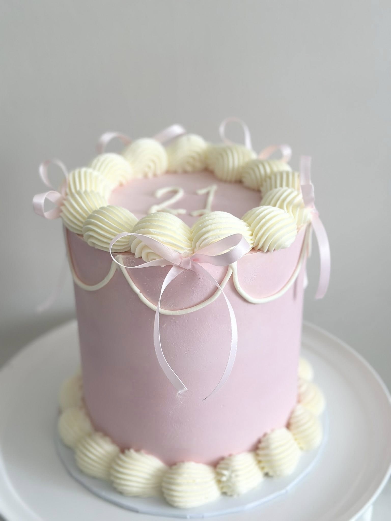 Pink layered cake with cream piping and ribbons