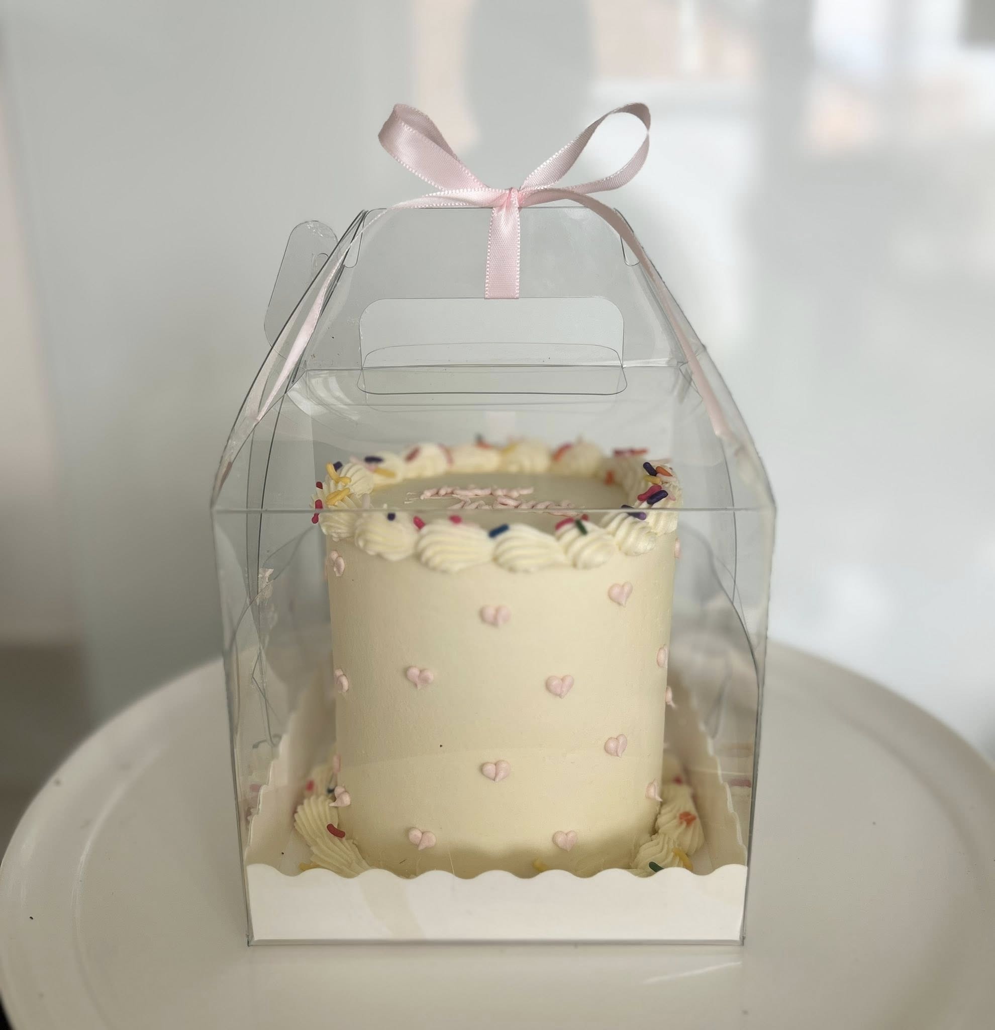 Elegant white cake with pink hearts in clear gift box