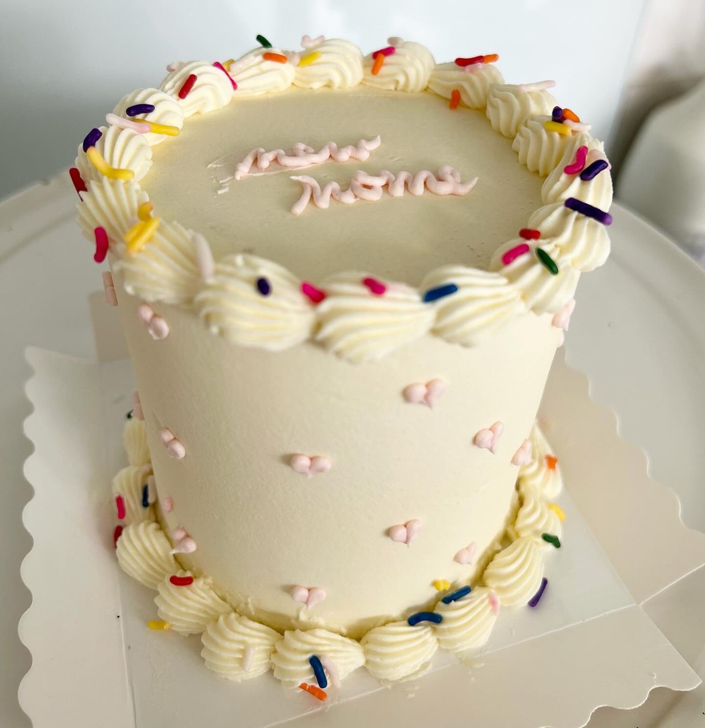 Elegant white tiered cake with colorful sprinkles and piping