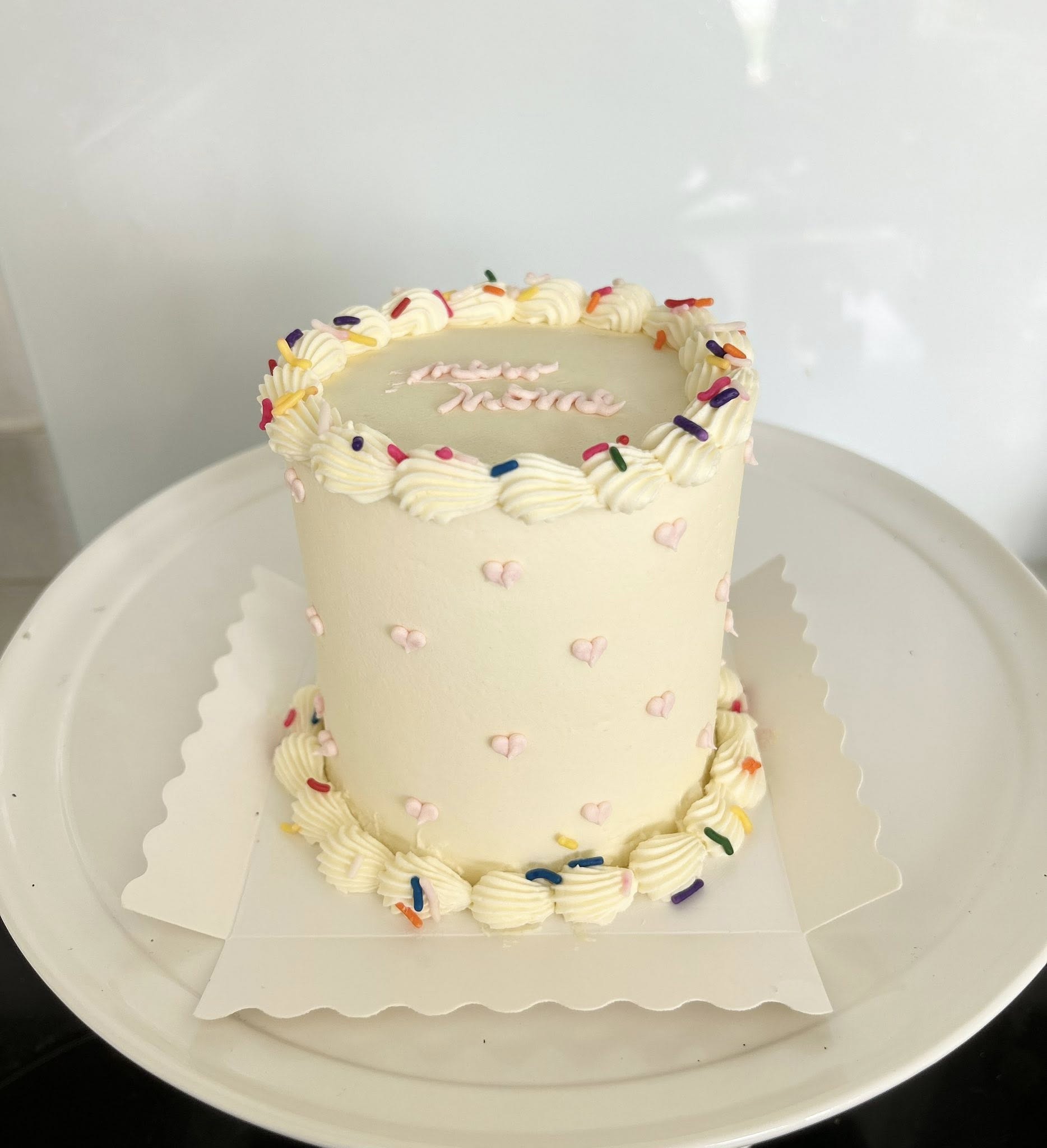 Elegant cream layer cake with colorful sprinkles and piping